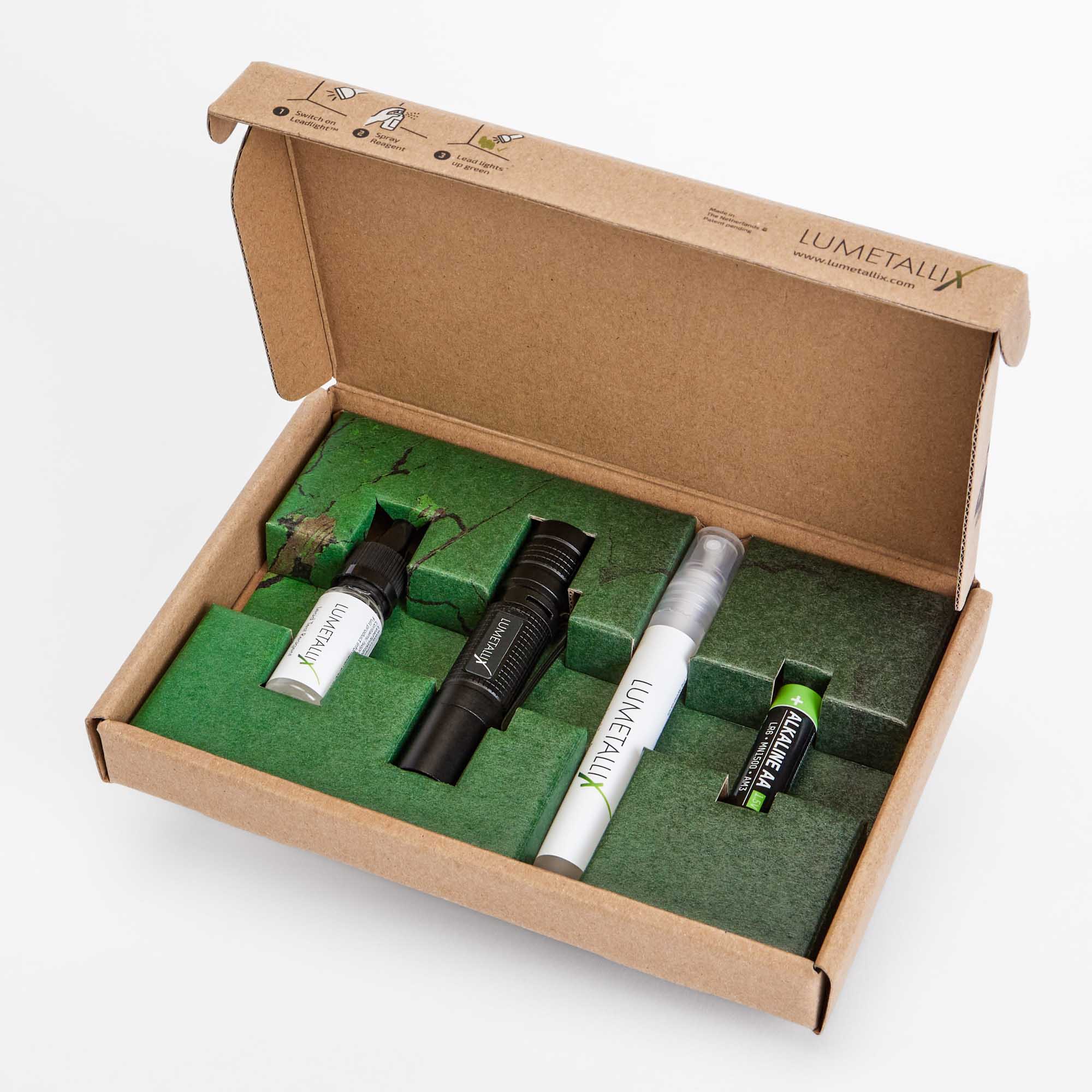 Lumetallix lead test kit unboxed, showing the LeadLight UV flashlight, drip bottle reagent, spray bottle reagent, and AA battery nested in green foam inside an eco-friendly kraft box. Made in the Netherlands, patent-pending, ready to use.